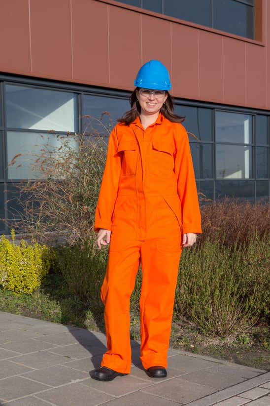 A Woman Wearing an Orange Coverall Suit and a Blue Hard Hat and Goggles